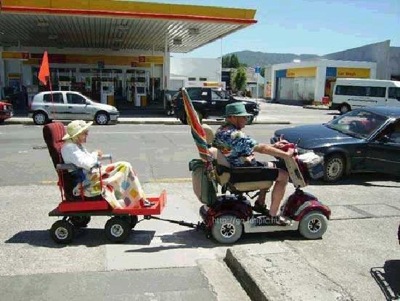 Two Elderly People riding a scooter and a trailer